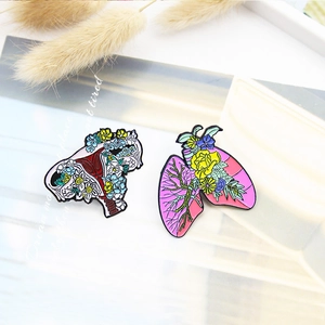 Artistic enamel pins featuring floral lung and uterus designs with vibrant colorful details