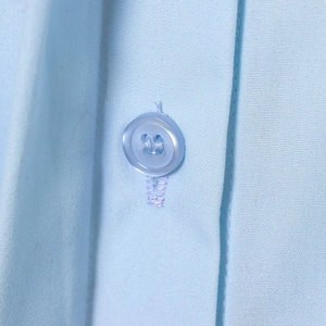 Close-up of light blue long sleeve shirt featuring fabric texture and clear button detail