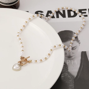 Detailed view of elegant pearl heart necklace featuring a vintage gold OT toggle closure
