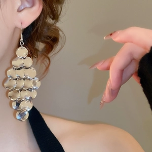 Close-up of silver layered metal disc drop earrings worn by a model in a side view