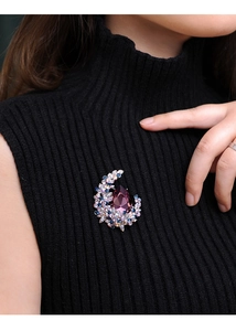 Detail of luxury crystal moon brooch with purple teardrop stone on black sweater