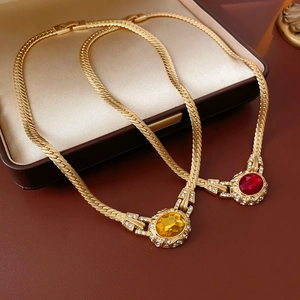 Detail of vintage gold snake chain necklaces with red and yellow gems in a velvet box