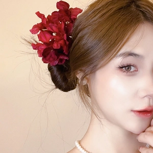 Detail of elegant large wine red fabric flower hair clip on a low bun hairstyle