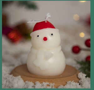 Macro shot of cute white snowman candle with red hat and cozy festive background