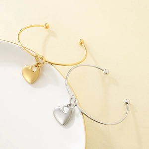 Detailed close-up of gold and silver heart pendant bangles on a ceramic plate