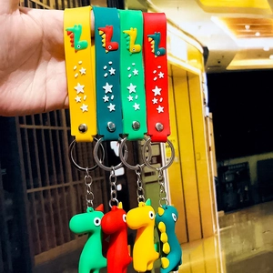 Detailed close-up of cute cartoon dinosaur keychains in yellow, cyan, green, and red colors