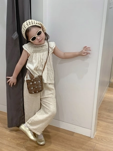 Detail of bohemian kids two-piece set featuring ruffled sleeveless top and wide-leg linen pants