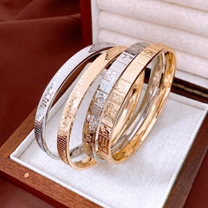 Detail of four metal bangles with scale texture and lucky Chinese characters in jewelry box