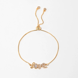 Macro detail of gold adjustable box chain bracelet with zircon-encrusted LOVE charm