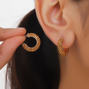 Close-up of amber crystal pavé hoop earrings worn by a model for fashion detail
