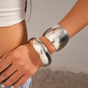 Detail view of two-piece hammered silver cuff bracelets worn by a model in a minimal setting