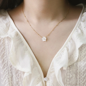 Detailed close-up of 18K gold-plated satellite chain with white shell flower pendant