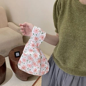 Close-up of a floral cotton wristlet bag held by a model in a cozy home setting