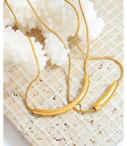 Détail de colliers pendentifs sourire en or 18K sur corail blanc avec chaînes serpent