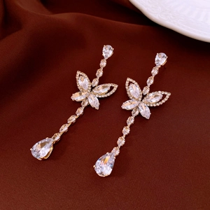 Detail of silver drop earrings with crystal butterflies on a luxury velvet background
