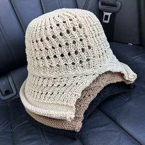 Close-up of three knitted hollow bucket hats in beige brown and black colors
