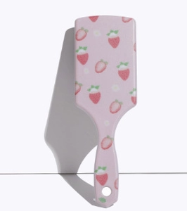 Detailed back view of a pink square hairbrush featuring cute strawberry prints and hanging hole