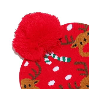 Close-up of red Christmas knit hat featuring reindeer, candy cane patterns and a plush pompom