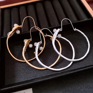 Irregular silver and gold hoop earrings with crystal pavé balls on a velvet tray