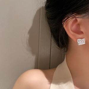 Gros plan de boucles d'oreilles géométriques argentées à texture irrégulière