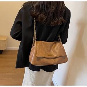 Vue détaillée du sac en cuir marron avec chaîne en métal doré sur l'épaule du mannequin