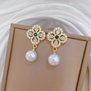 Detail of clover earrings with green stone, zircons and white pearl in a jewelry box