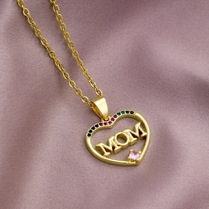 Close-up of golden MOM heart pendant with colorful zircon stones on purple satin