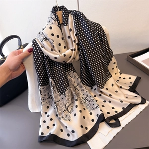 Elegant leopard and polka dot print silk scarf draped over a wooden hanger with a sweater