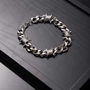 Silver Cuban link bracelet with barbed wire design on black wood display tray