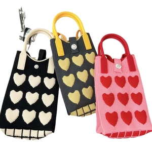 Three mini knitted bags with heart patterns and checkered bottoms in various colors