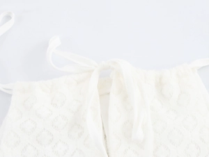 Detail of white knit dress with diamond texture and elegant drawstring halter neckline
