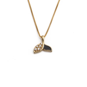 Detailed macro shot of a gold fishtail pendant with black enamel and zircon stones