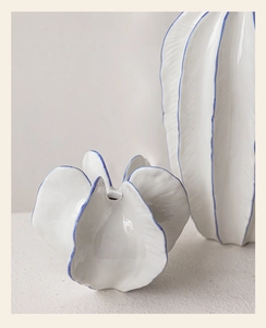 Detalle de jarrones de cerámica blanca con bordes azules y texturas modernas de ondas