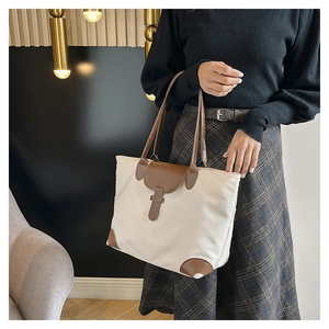 Detail of nylon tote bag with brown leather trim and buckles in casual carry style