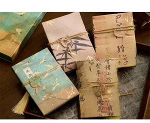Close-up of four handmade paper notebooks with classical calligraphy and hemp rope ties