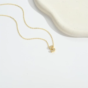 Gold-plated letter S initial necklace with cubic zirconia paving on white surface