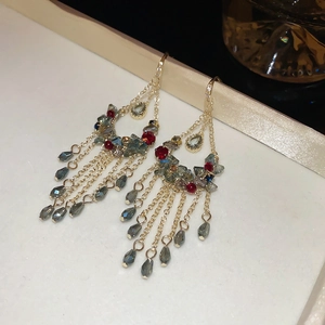 Detailed close-up of gold flower earrings with colorful crystals and long tassel chains