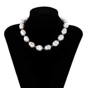 Detail showing white baroque irregular pearls and gold metal rings on a black mannequin