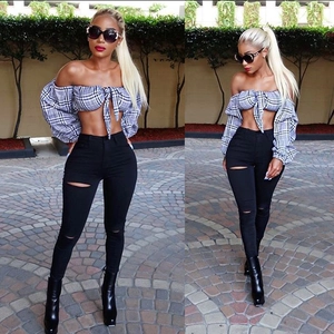 Detail of high waisted ripped skinny jeans paired with a checkered crop top and boots