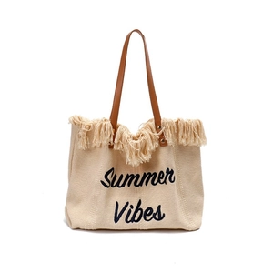 Detail of Summer Vibes embroidery on canvas tote bag with brown leather handles and fringes