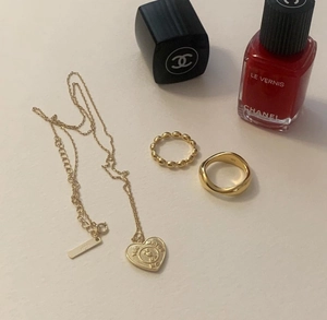 Detail view of 925 silver heart necklace and gold rings with engraved lettering on surface