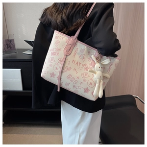 Dettaglio della borsa tote con motivi graffiti rosa e ciondolo a forma di coniglio bianco