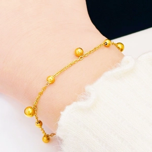 Elegant gold bead chain bracelet in titanium steel shown on a model's wrist with a white sweater