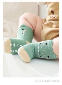 Close-up of mint green baby anti-slip cotton socks with 3D dinosaur cartoon pattern