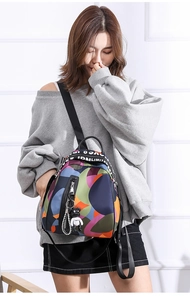 Close-up of a mini patterned backpack with colorful geometric print and bear pendant