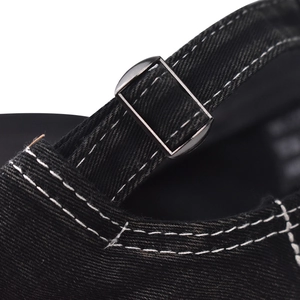 Macro shot of adjustable metal buckle and contrast stitching on black denim baseball cap