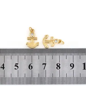 Macro shot of 18K gold plated anchor pendants with cubic zirconia inlay on white background
