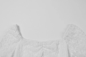 Détail de la dentelle florale blanche et de l'encolure carrée de cette robe