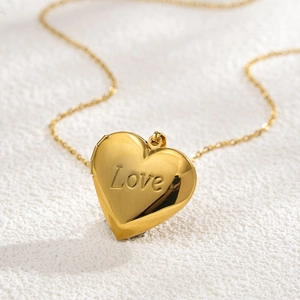 Detail shot of golden 316L stainless steel heart locket with Love script engraving