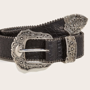 Detail of black faux crocodile belt featuring an ornate silver western style buckle